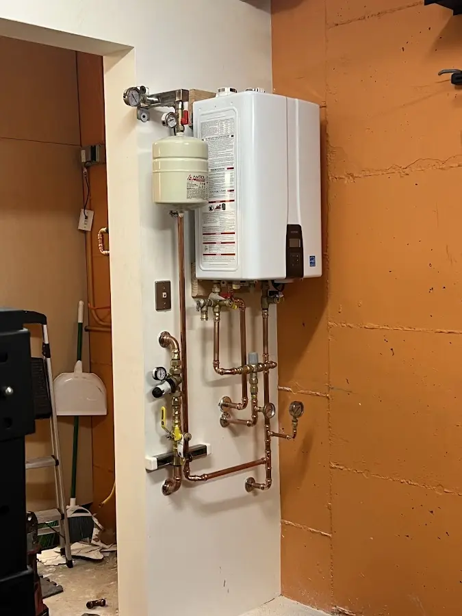 Plumbing technician inspecting water heater connections in High Point